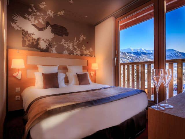 Primary bedroom with queen bed and private balcony access to mountain views