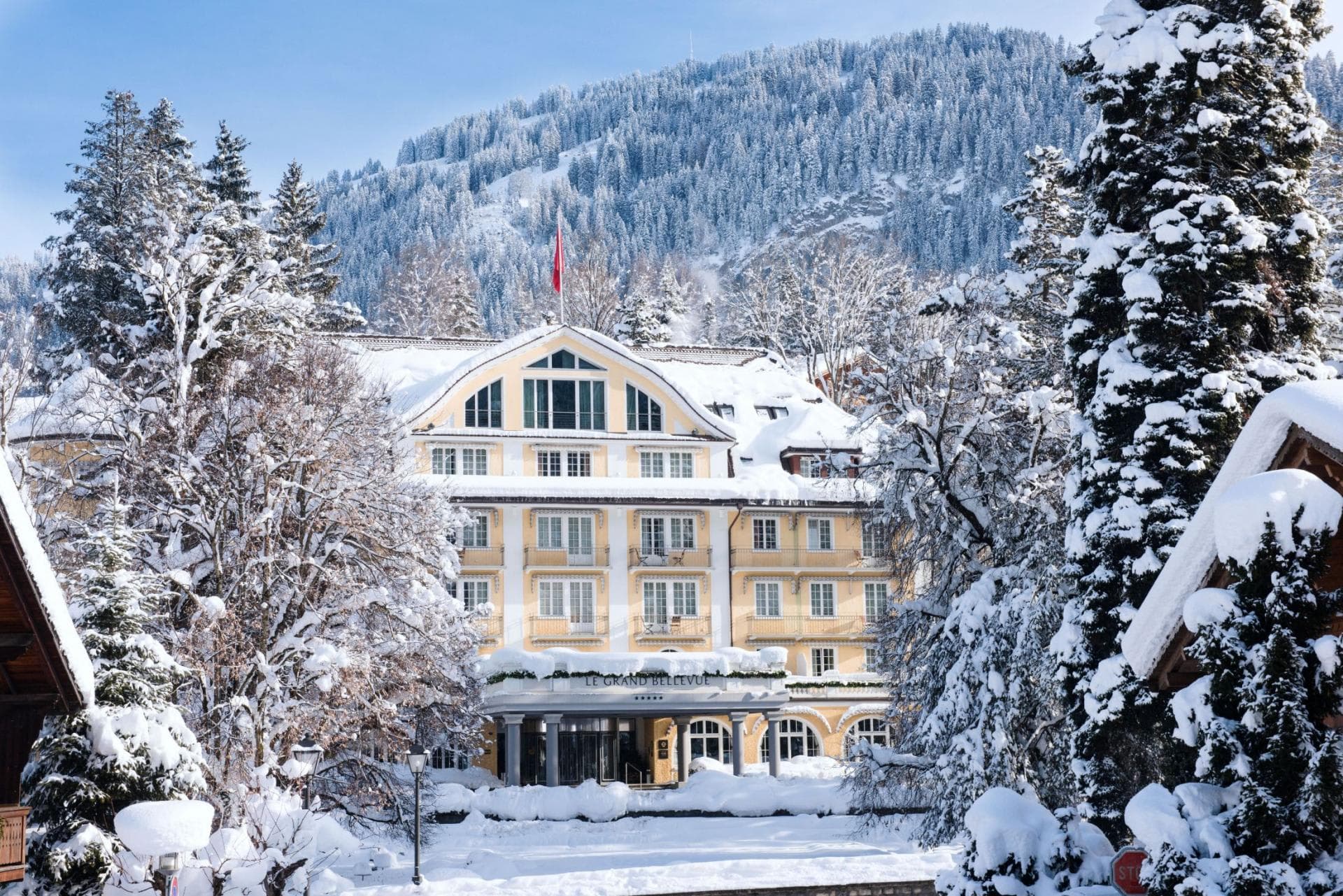 Hotel exterior with private balconies and mountain backdrop during winter