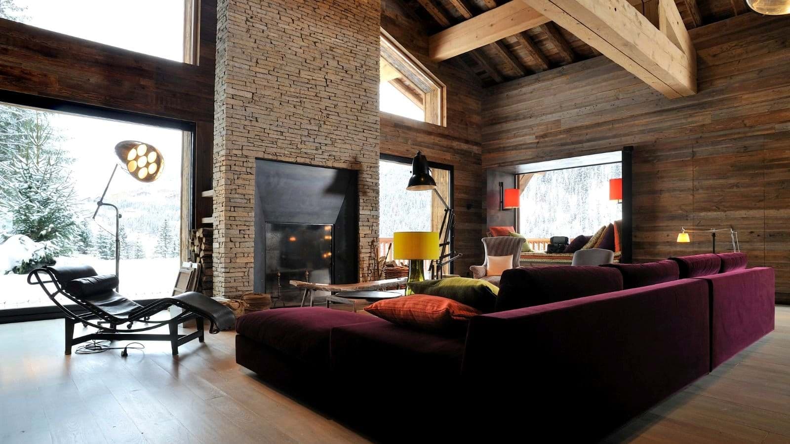 Living area with floor-to-ceiling fireplace and window seat overlooking snowy landscape