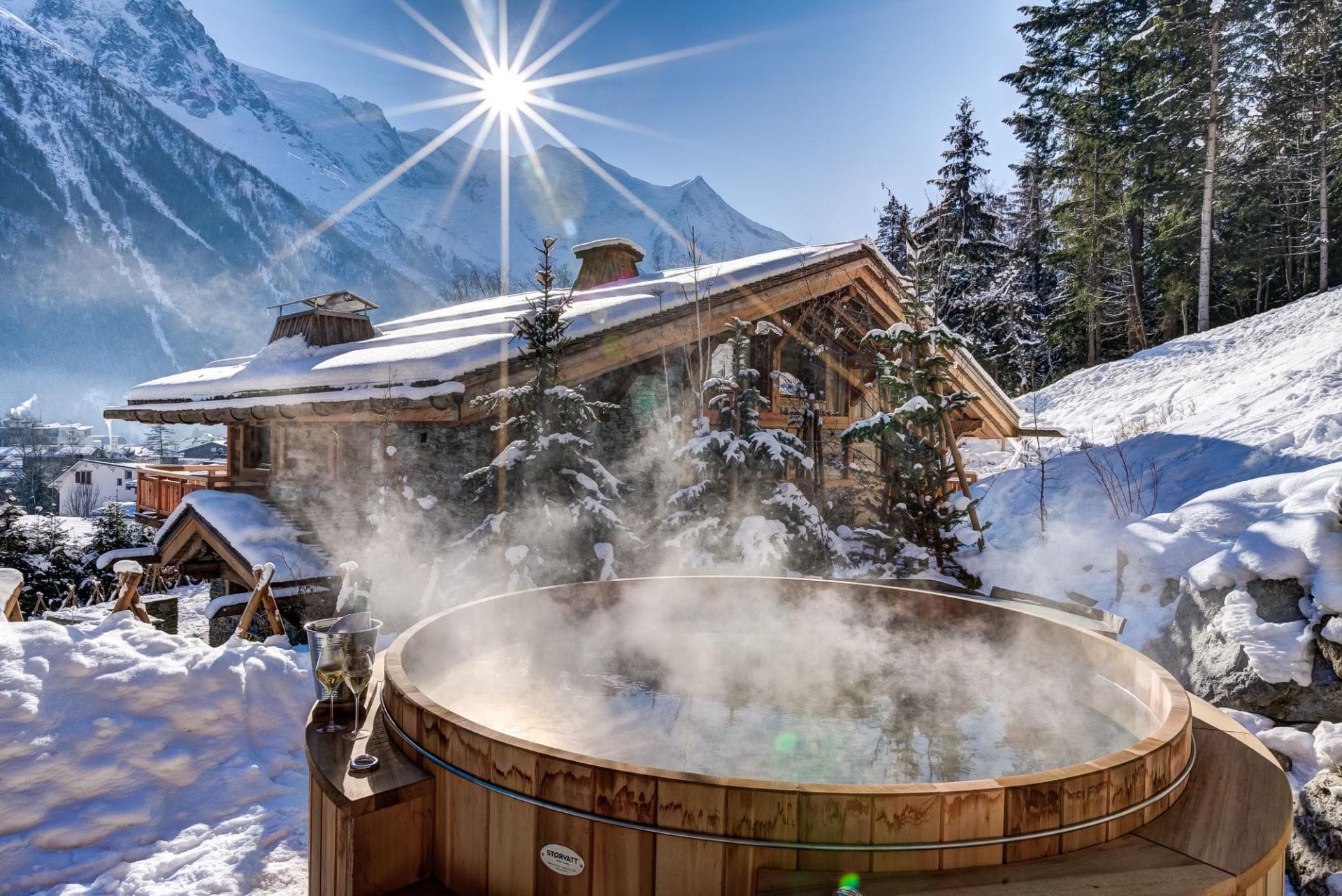Outdoor cedar hot tub with mountain views and adjacent chalet
