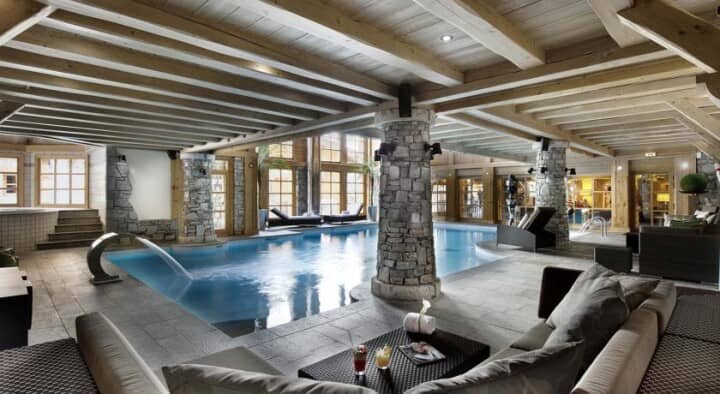 Indoor pool with waterfall feature and elevated hot tub