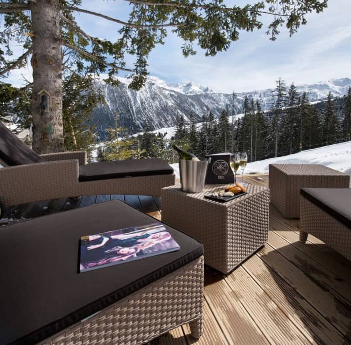 Sun deck with wicker lounge seating and snowy mountain views
