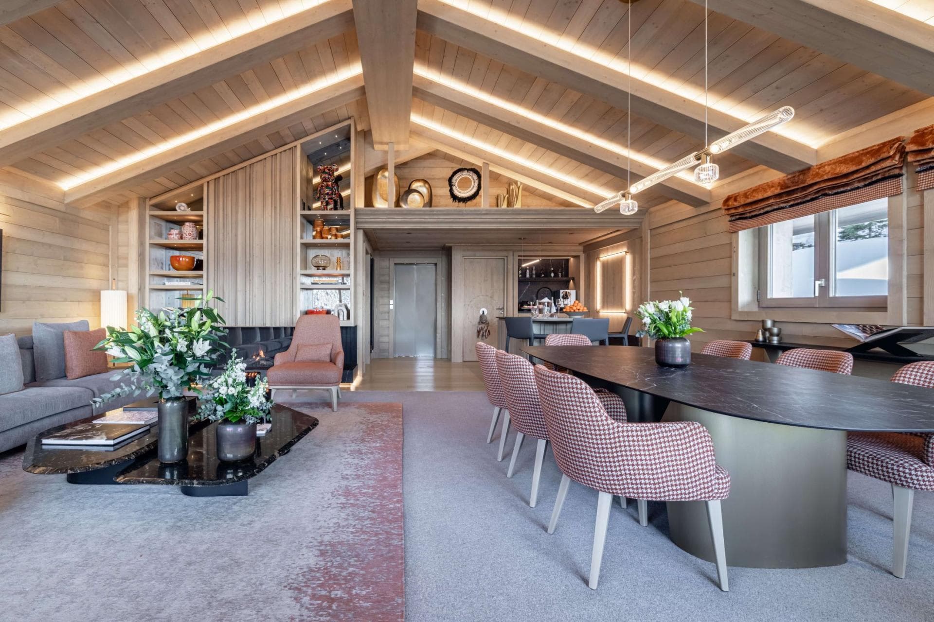 Open-plan living area with vaulted wood ceilings, elevator access, and dining for 8