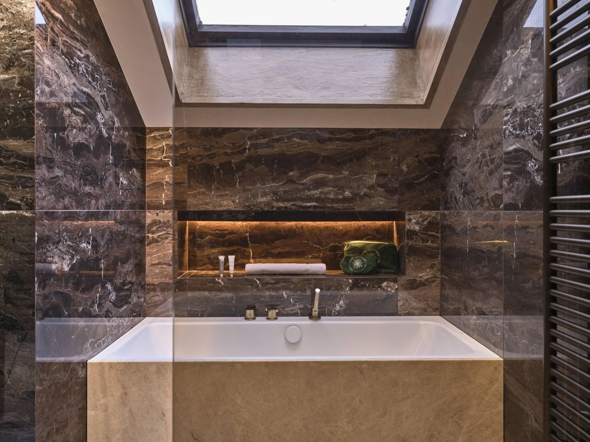 Bathroom with soaking tub, marble walls, and overhead skylight