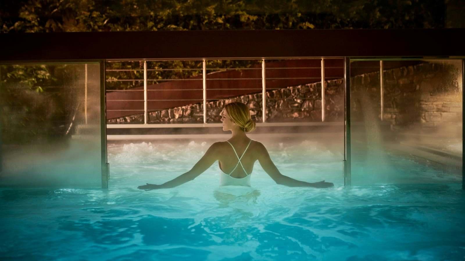 Heated indoor-outdoor infinity pool with swim-through glass divider