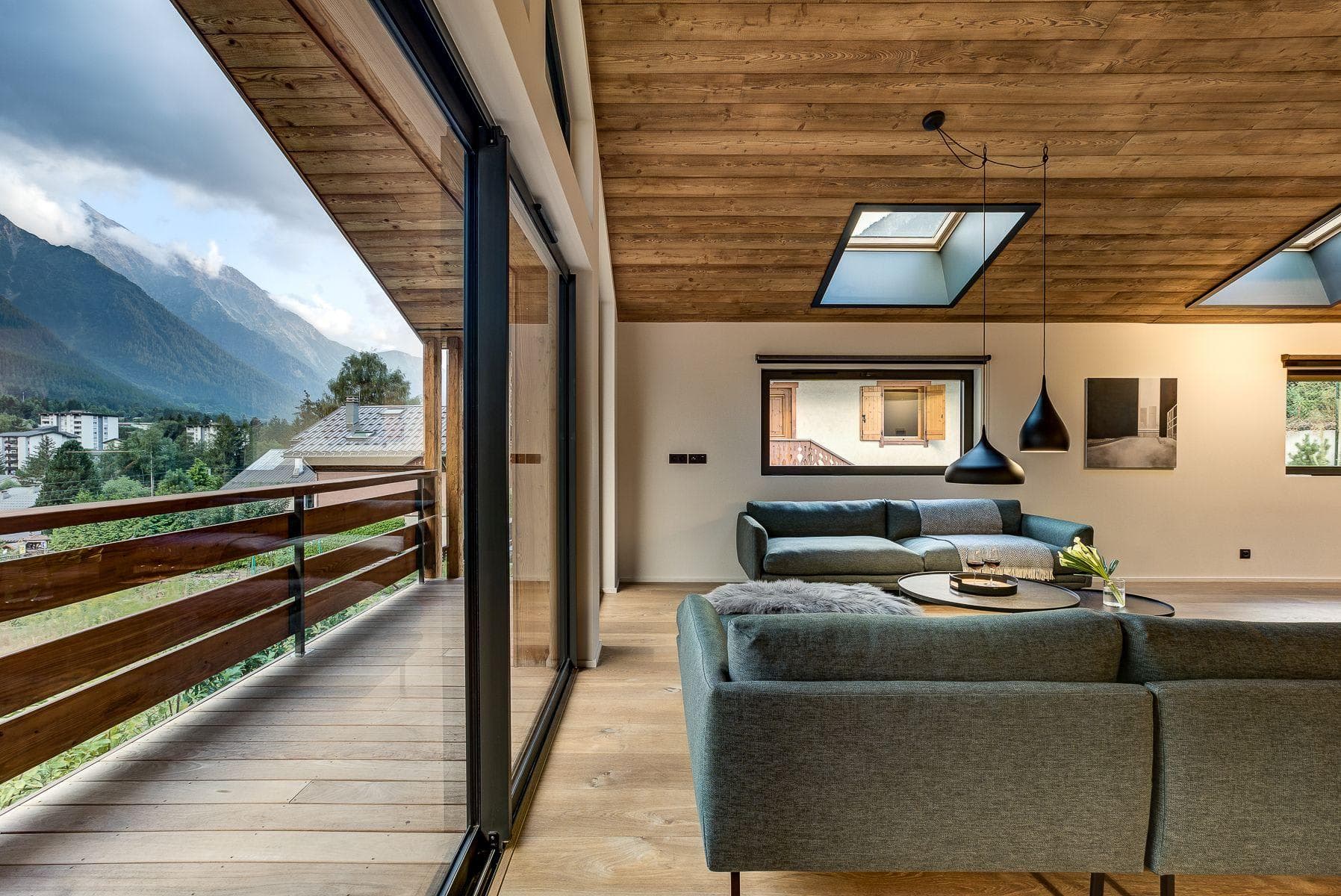 Living area with wood-paneled ceiling, skylights, and mountain-view balcony