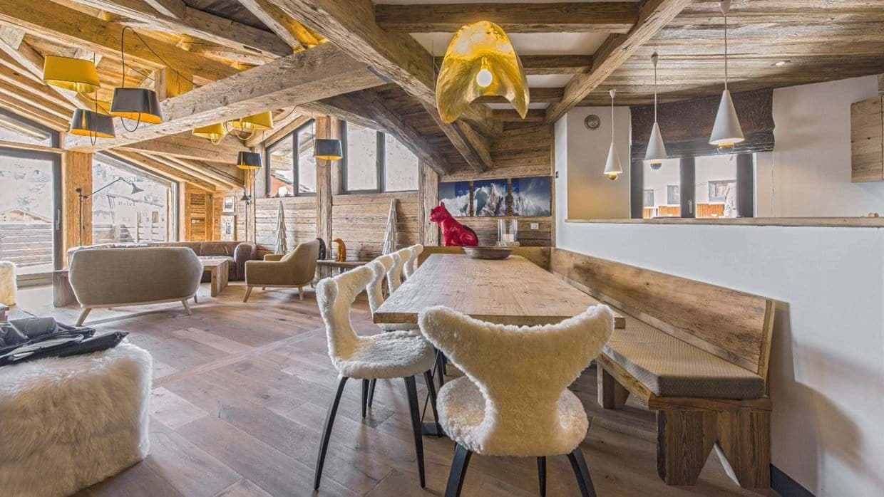 Open-plan dining area with banquet seating and reclaimed wood beams