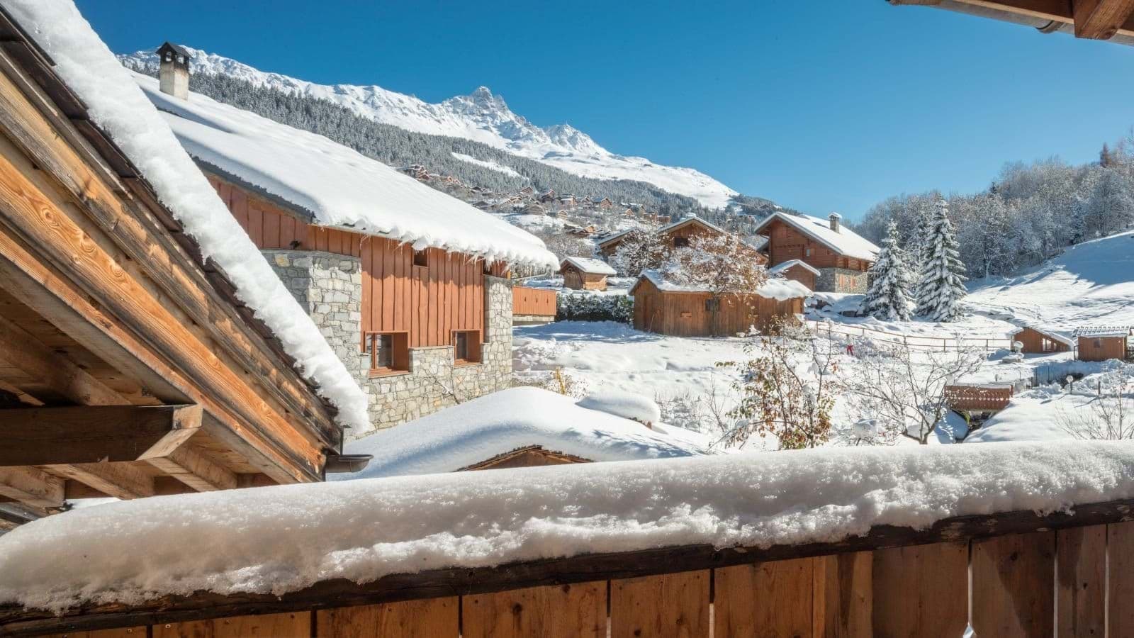 Balcony view overlooking snow-covered chalets and mountain peaks