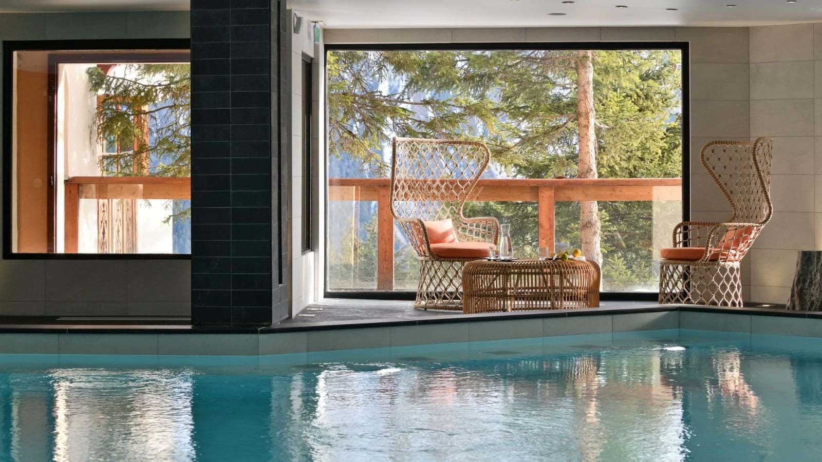 Indoor pool area with mountain-view seating and floor-to-ceiling windows
