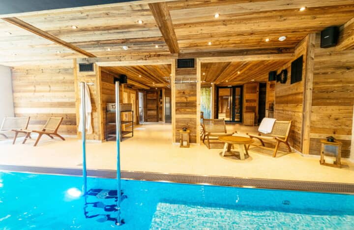 Indoor pool area with lounge seating and rustic timber walls