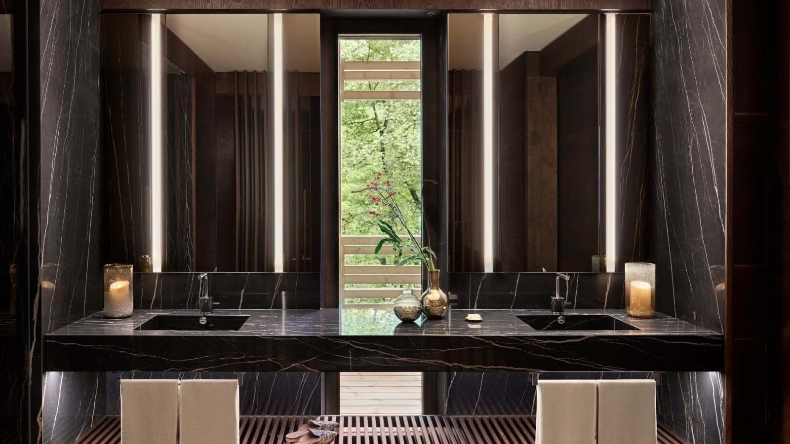 Bathroom with dual vanity, marble finishes, and vertical LED mirrors