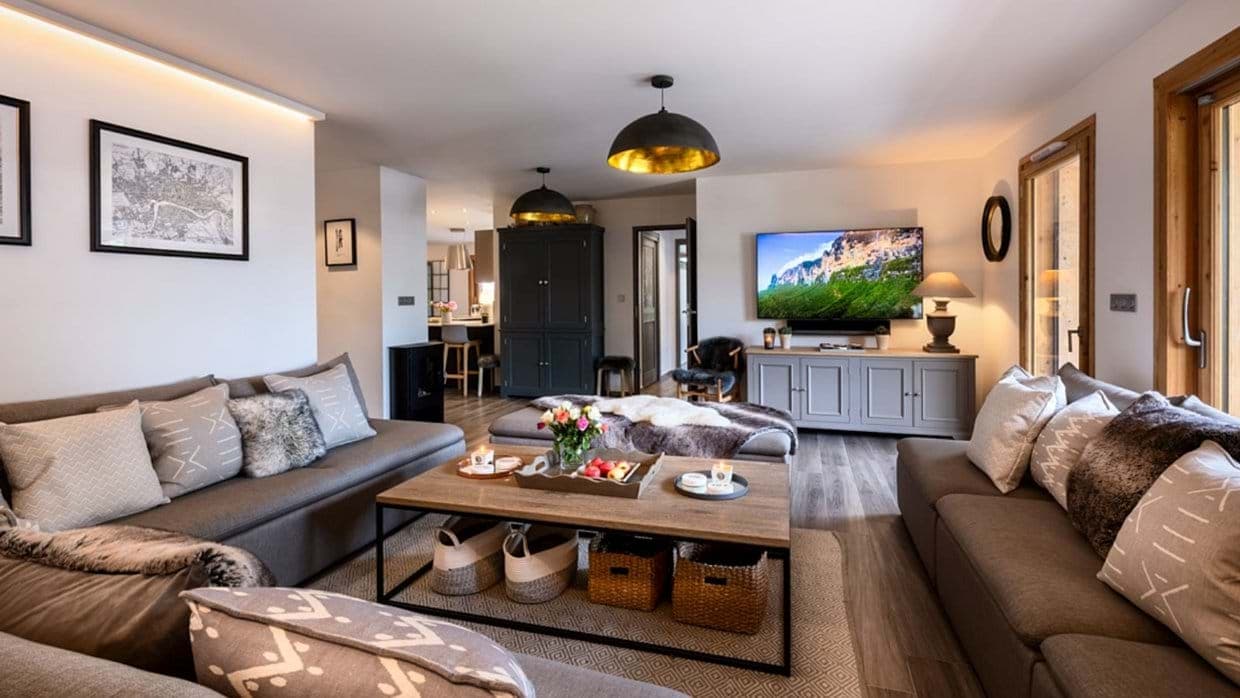 Living room with dual sofas, wood-burning stove, and wall-mounted TV