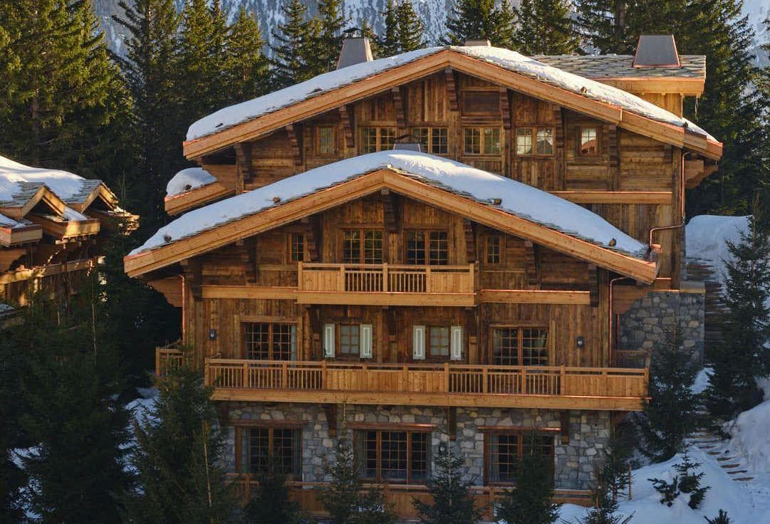 Three-story log and stone chalet with wraparound decks and snow-capped roof