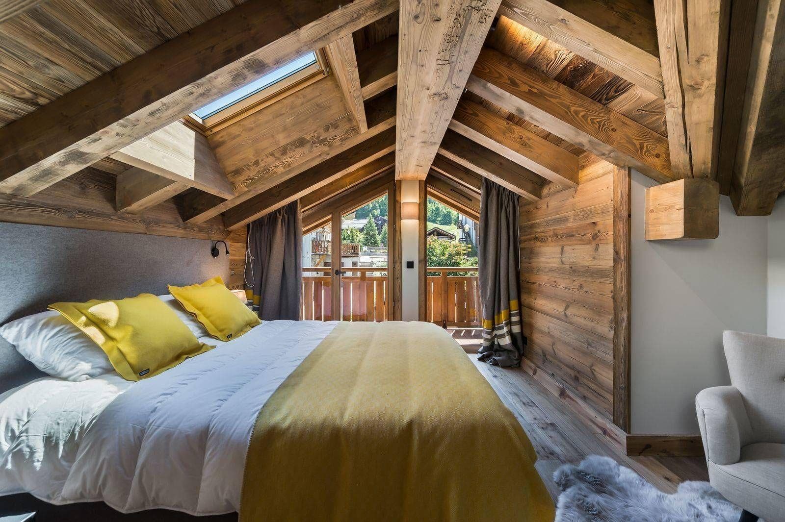 Attic bedroom with vaulted beam ceiling, skylight, and balcony access