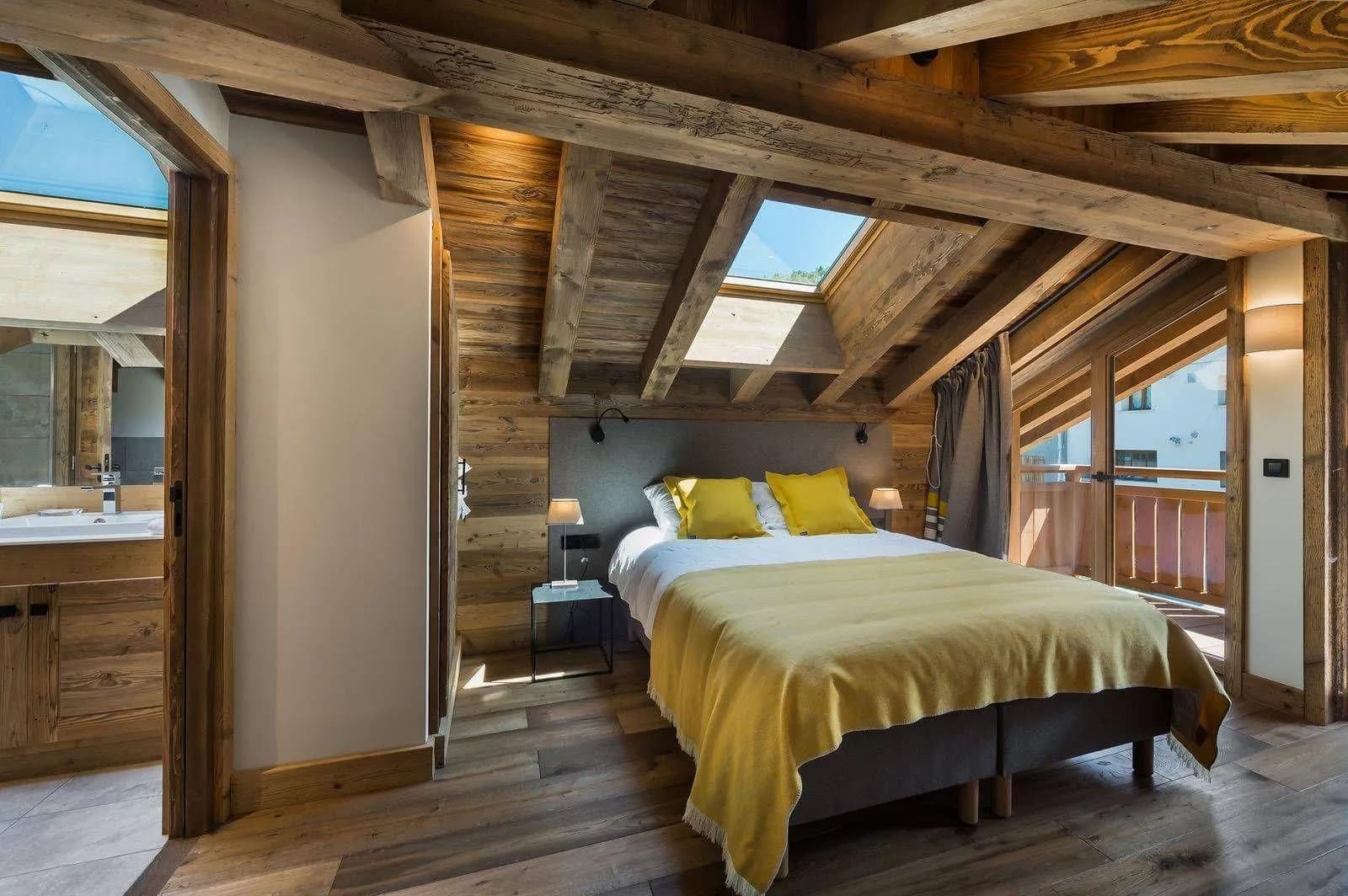 Double bedroom beneath timber beams with balcony doors