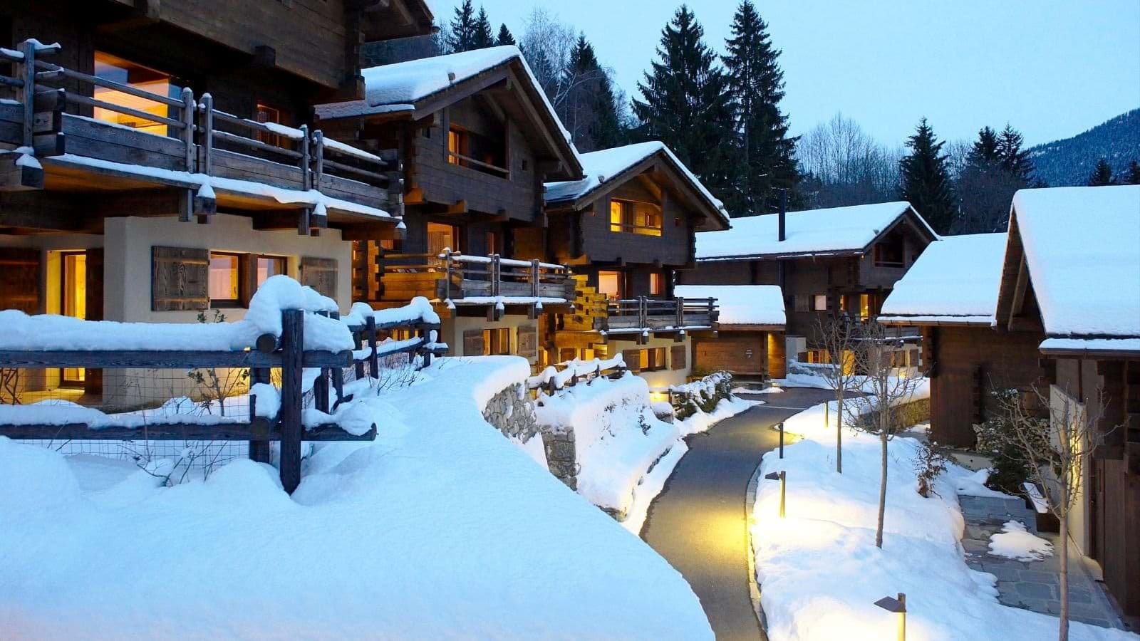 Timber lodge exteriors with private balconies and illuminated snow-free paths