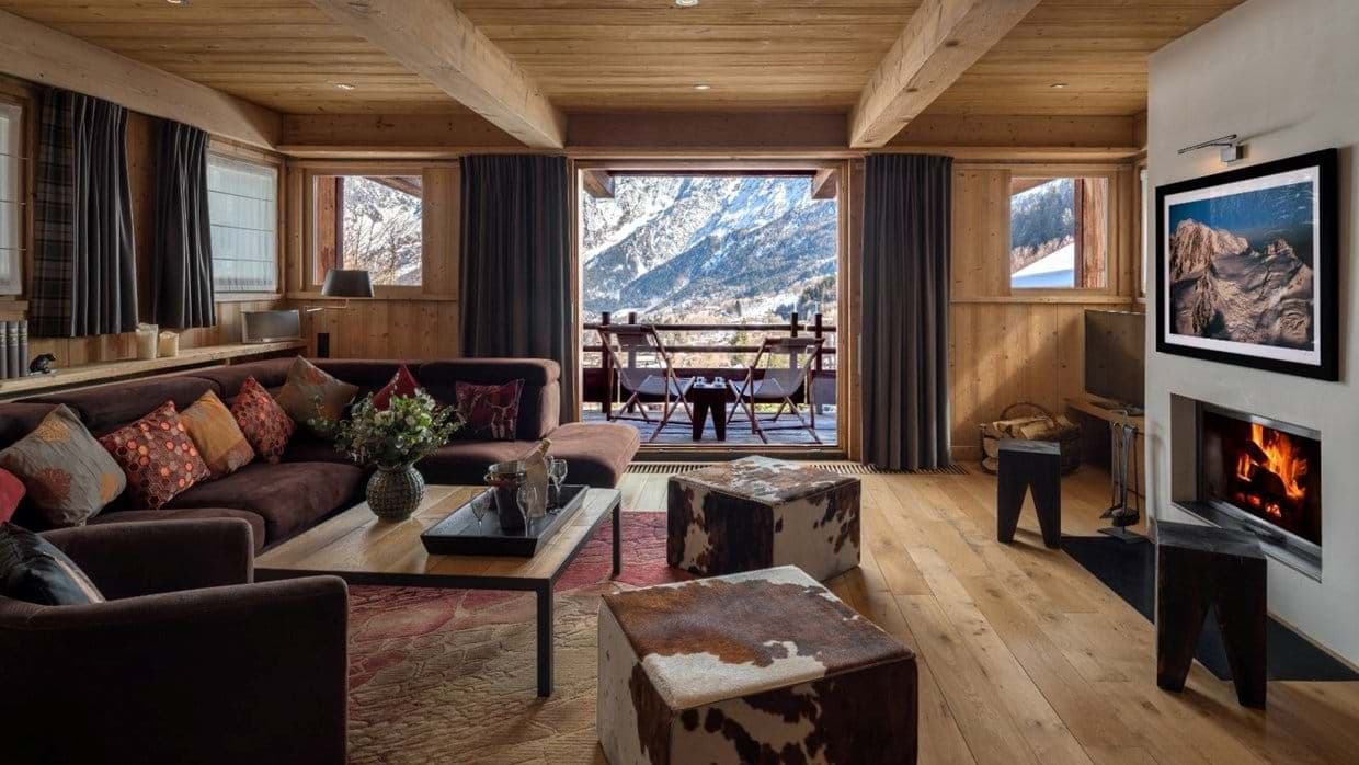 Living room with wood-burning fireplace and balcony with mountain views
