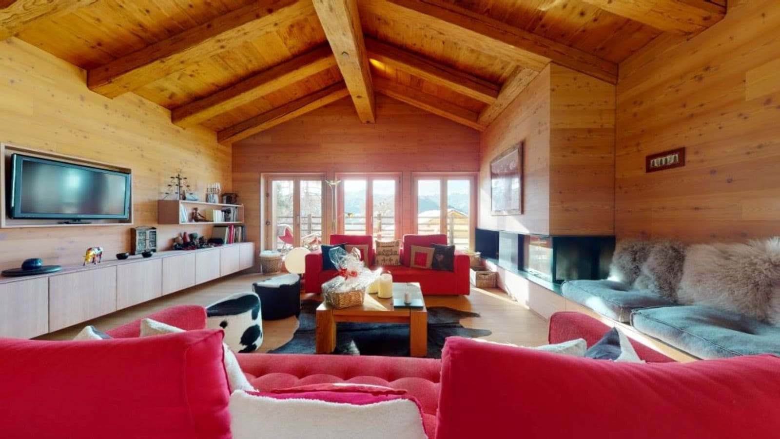 Living area with wood-paneled walls, vaulted ceilings, and glass-enclosed fireplace