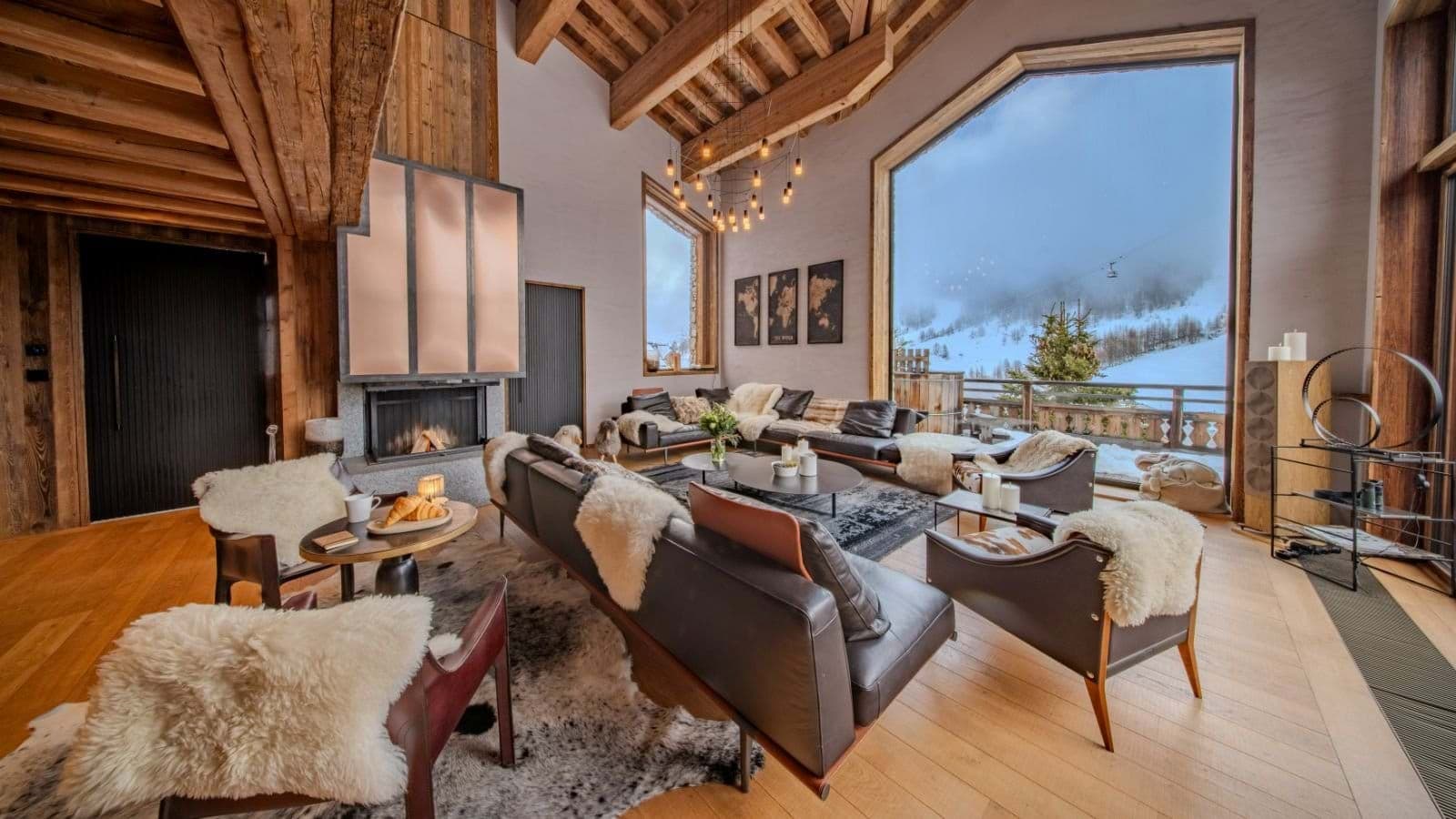 Living area with wood-burning fireplace and floor-to-ceiling ski slope views