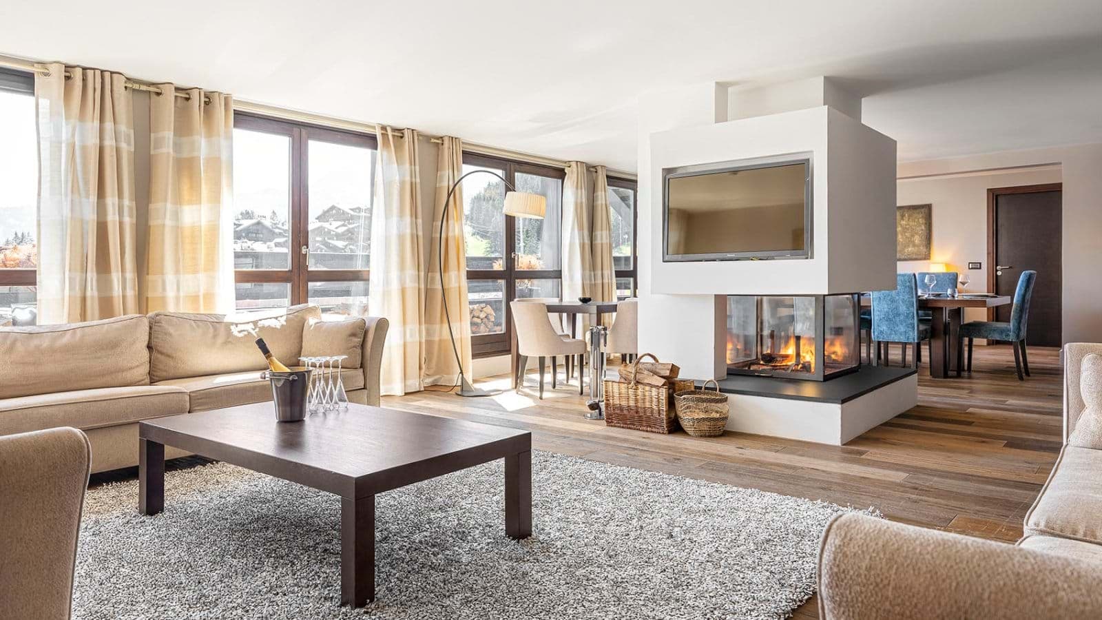 Open-plan living area featuring three-sided glass fireplace and mounted TV
