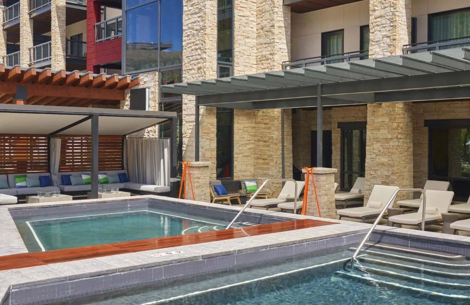 Shared outdoor pool and hot tub with poolside lounge seating and cabanas