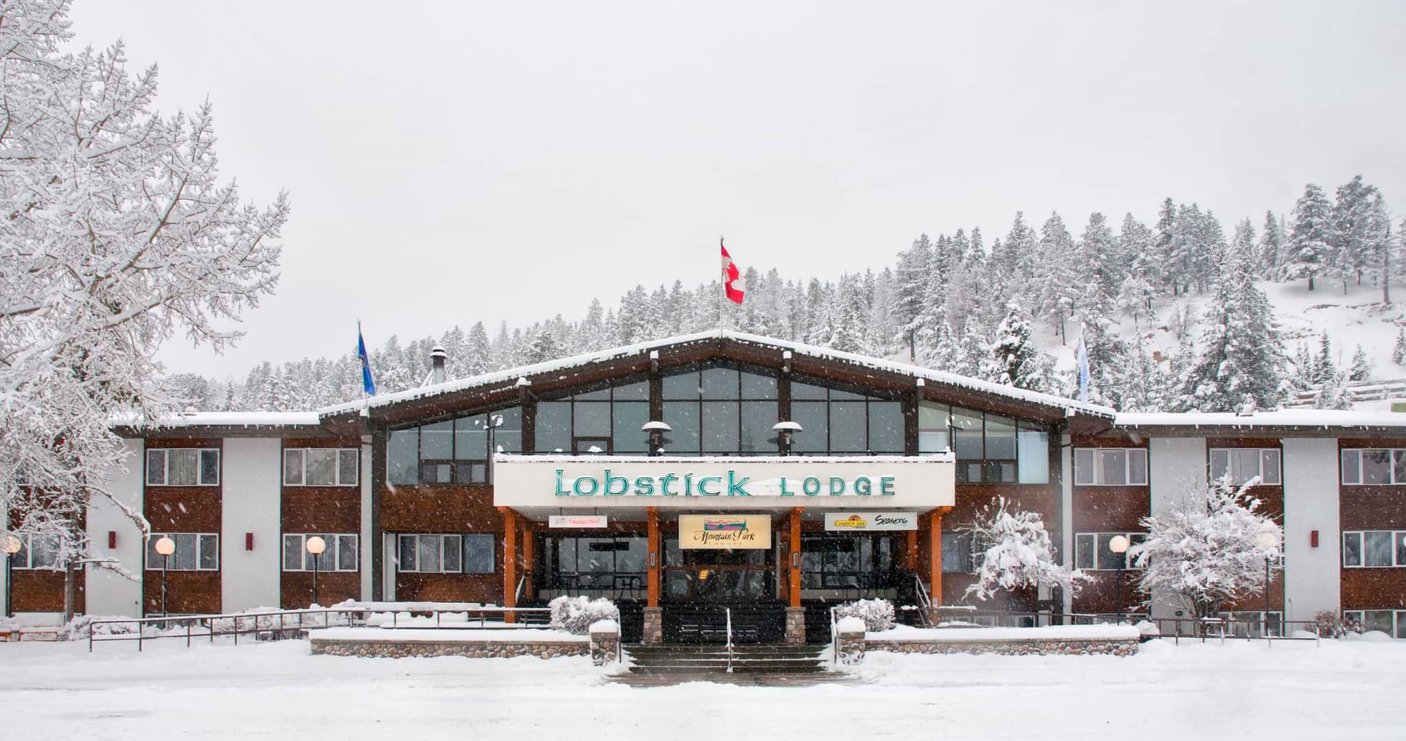 Lodge exterior with covered entrance and snow-covered evergreen backdrop