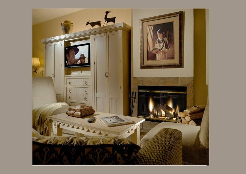 Primary bedroom with fireplace, built-in TV cabinet, and sitting area with seating for two