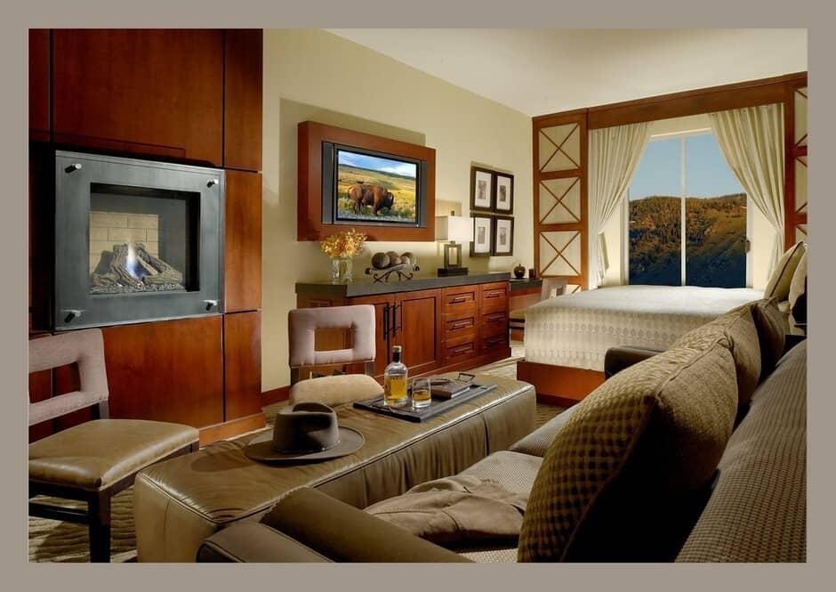 Master suite with fireplace, dual beds, and expansive forest views through floor-to-ceiling windows