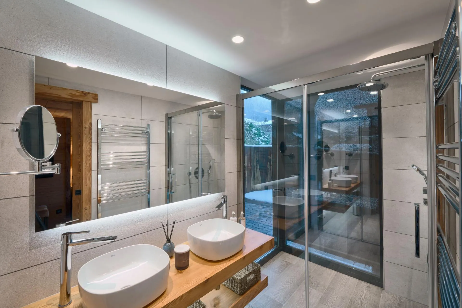 Bathroom with dual vessel sinks, walk-in shower, and heated towel rack