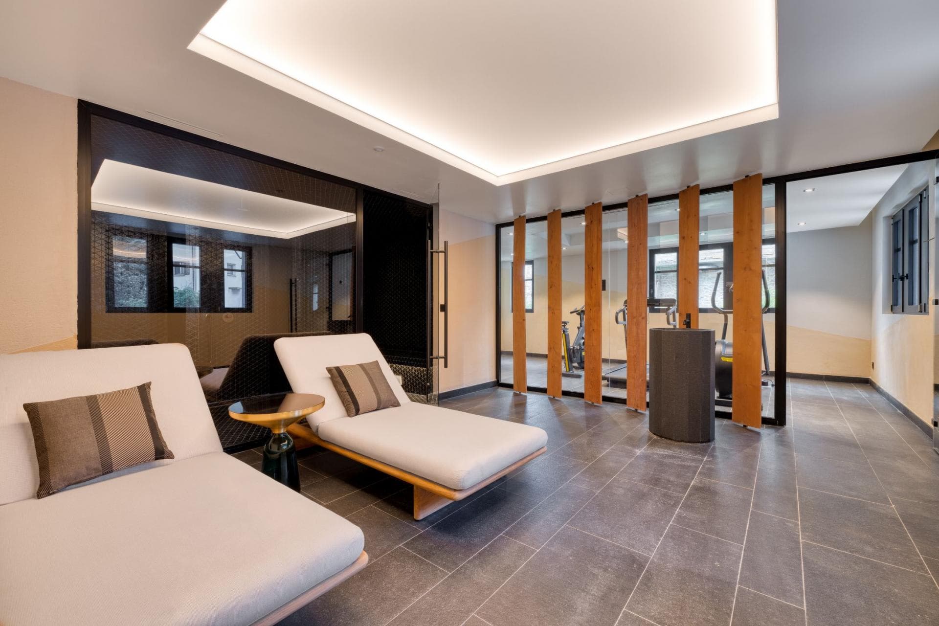 Wellness lounge with daybeds; adjacent gym with treadmill and stationary bike