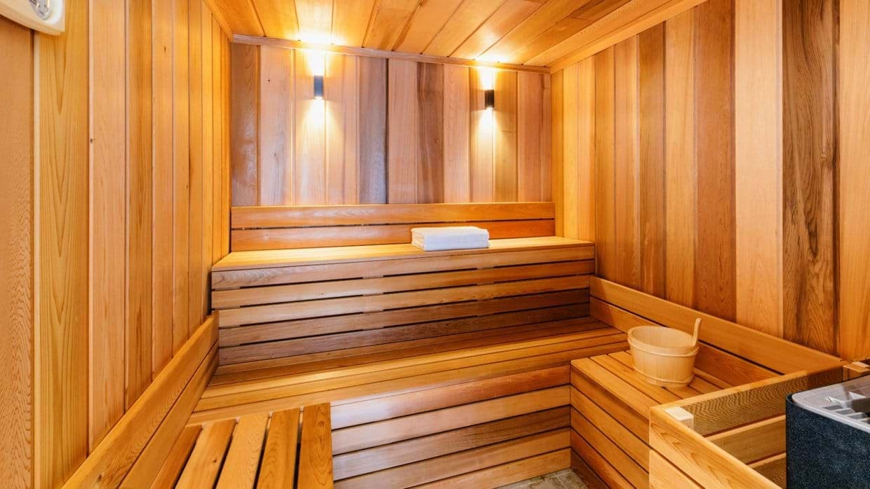 Cedar sauna featuring two-tier seating and traditional bucket with ladle