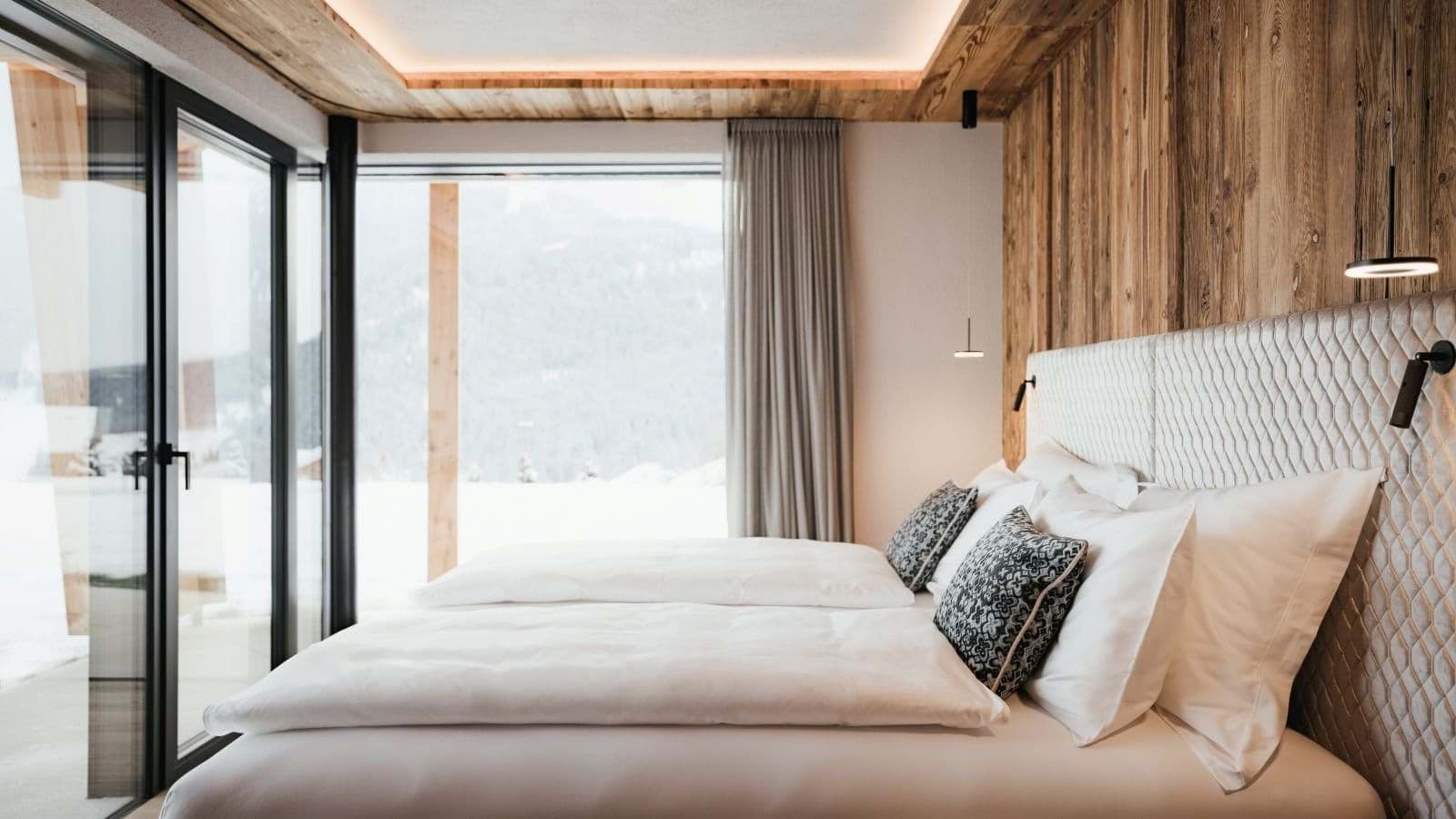 Bedroom with floor-to-ceiling windows and terrace access; mountain views