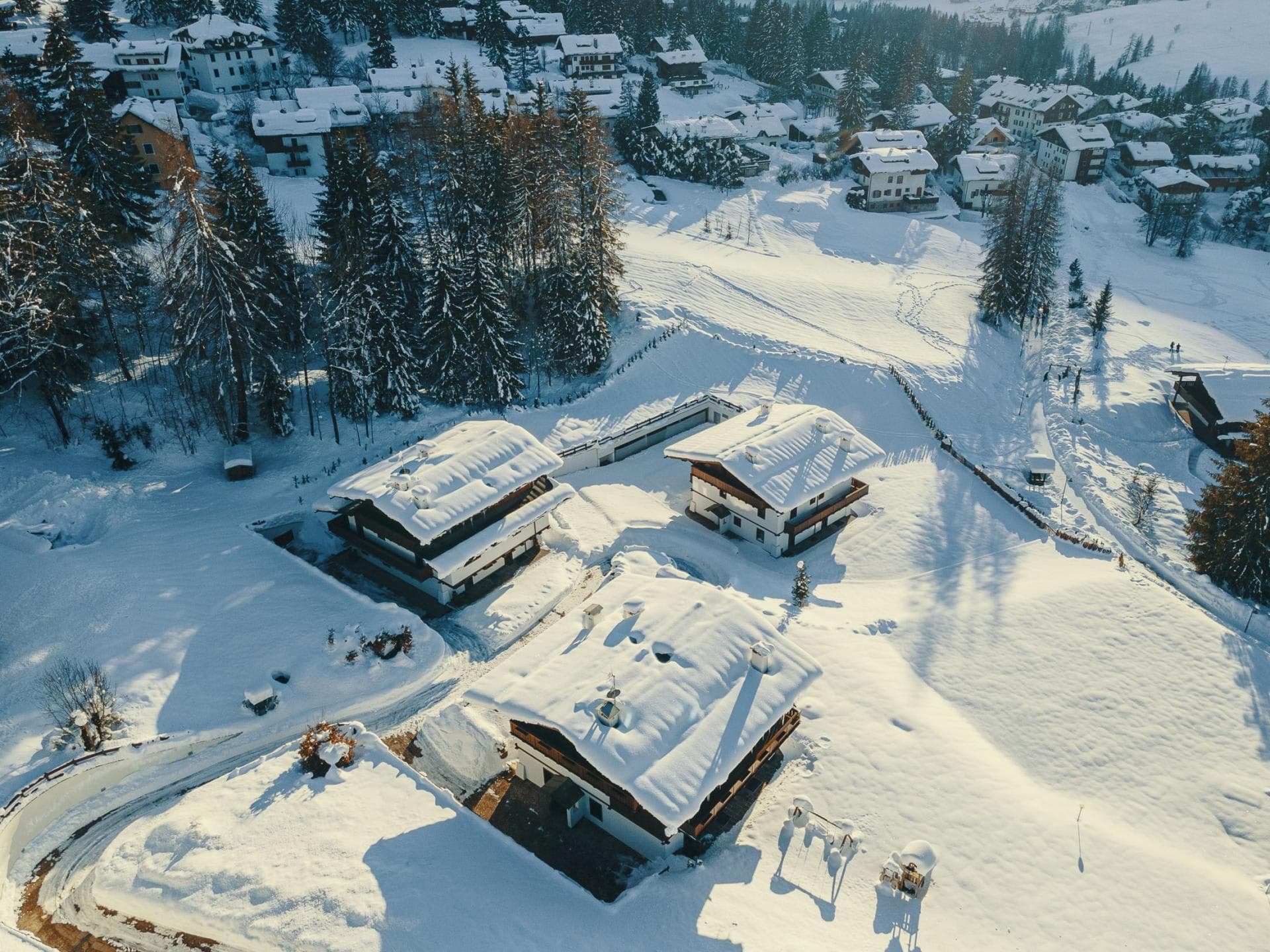 Aerial view of chalet complex with direct ski-in/ski-out access and forest border