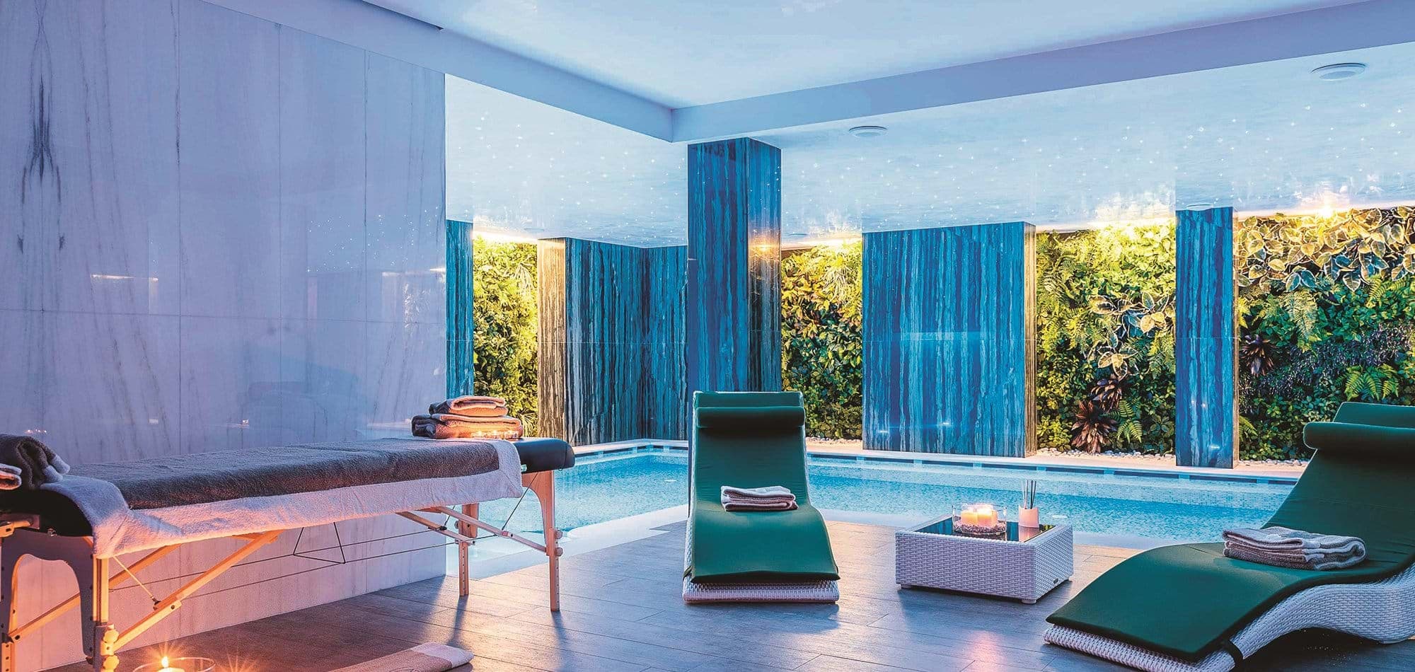 Indoor pool and spa area with massage table and living green walls