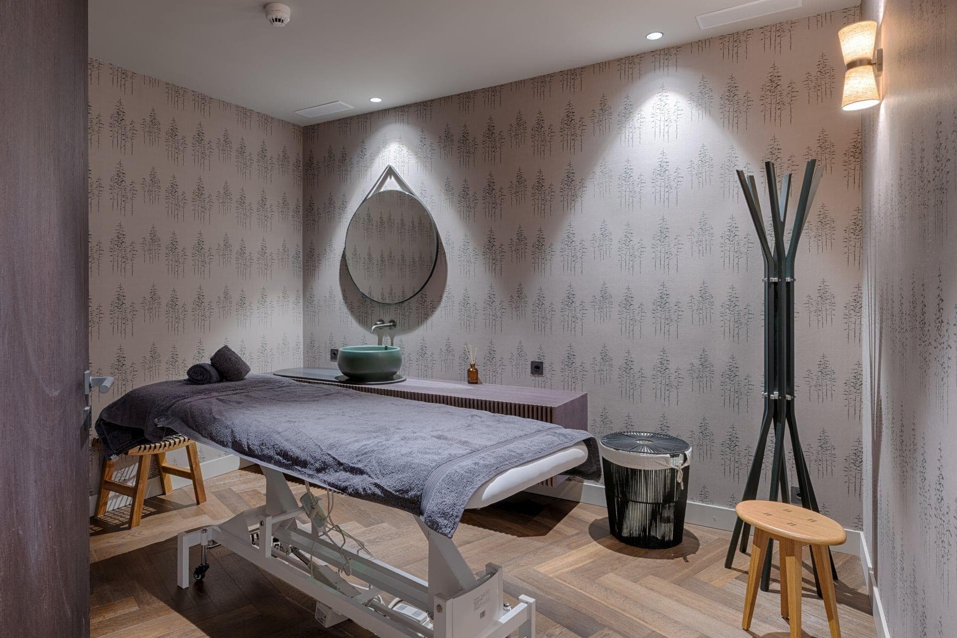 Private treatment room with massage table, vessel sink, and parquet flooring