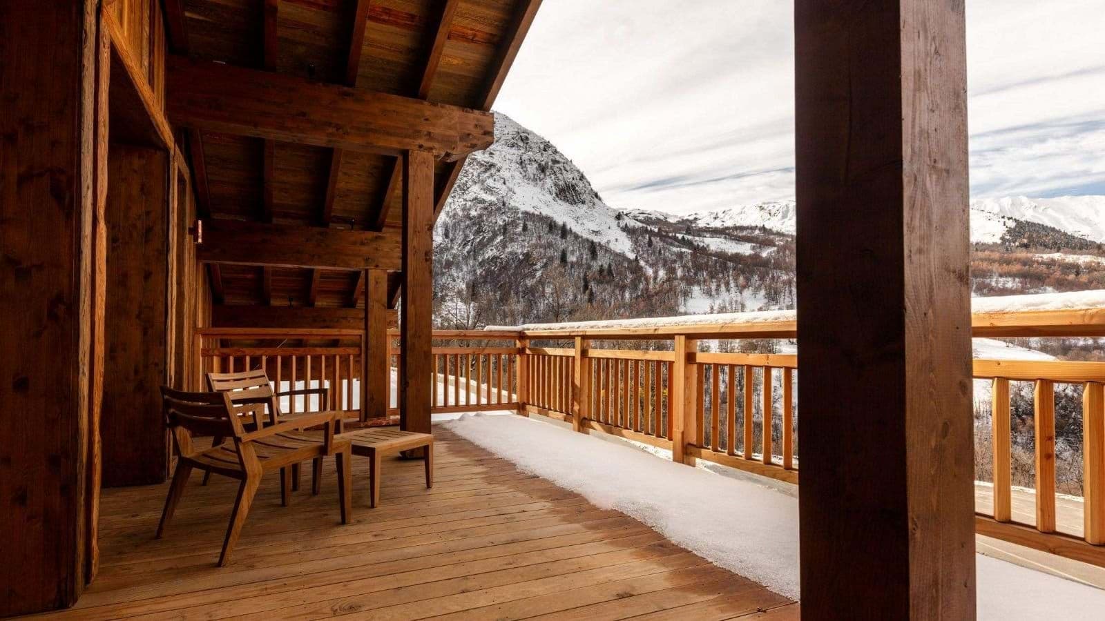 Covered timber balcony with lounge seating and panoramic alpine views