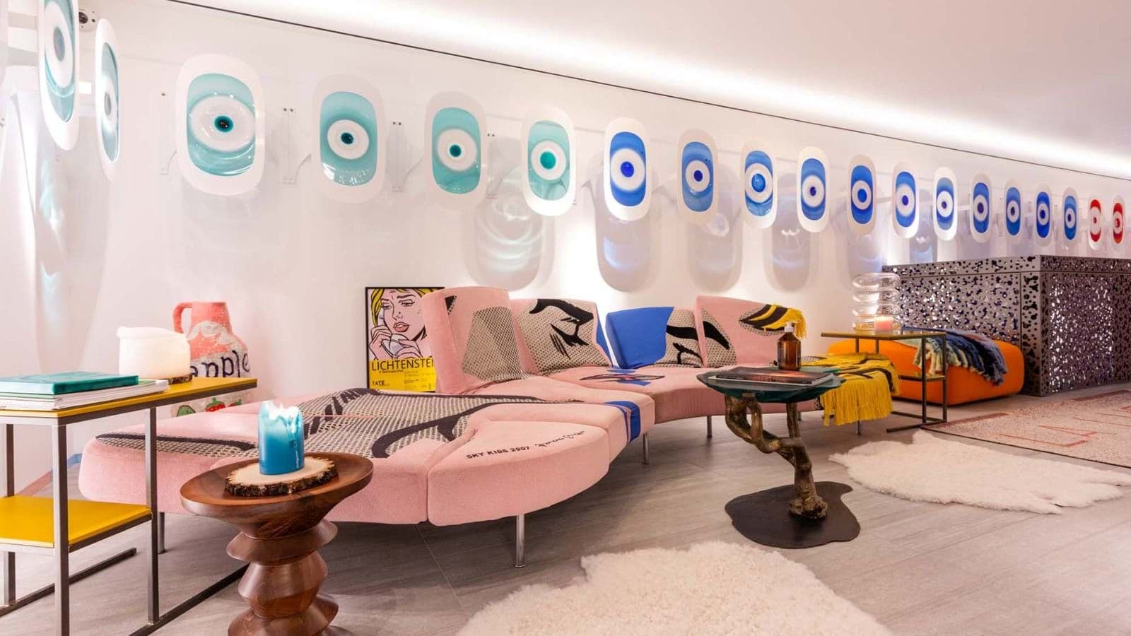 Lounge with pink graphic-print sectional and custom eye-motif wall lighting