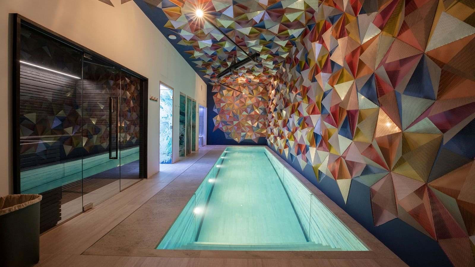 Lap pool and sauna with colorful geometric wall installation