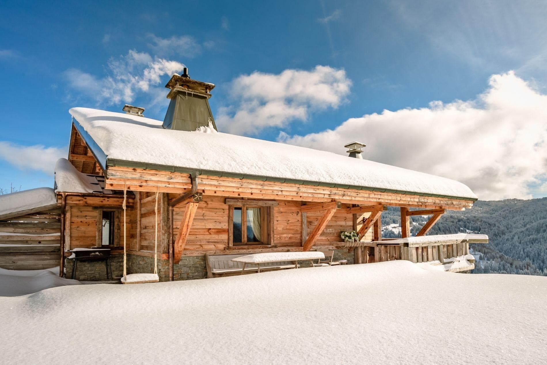 Timber chalet exterior with covered porch, bench seating, and valley views