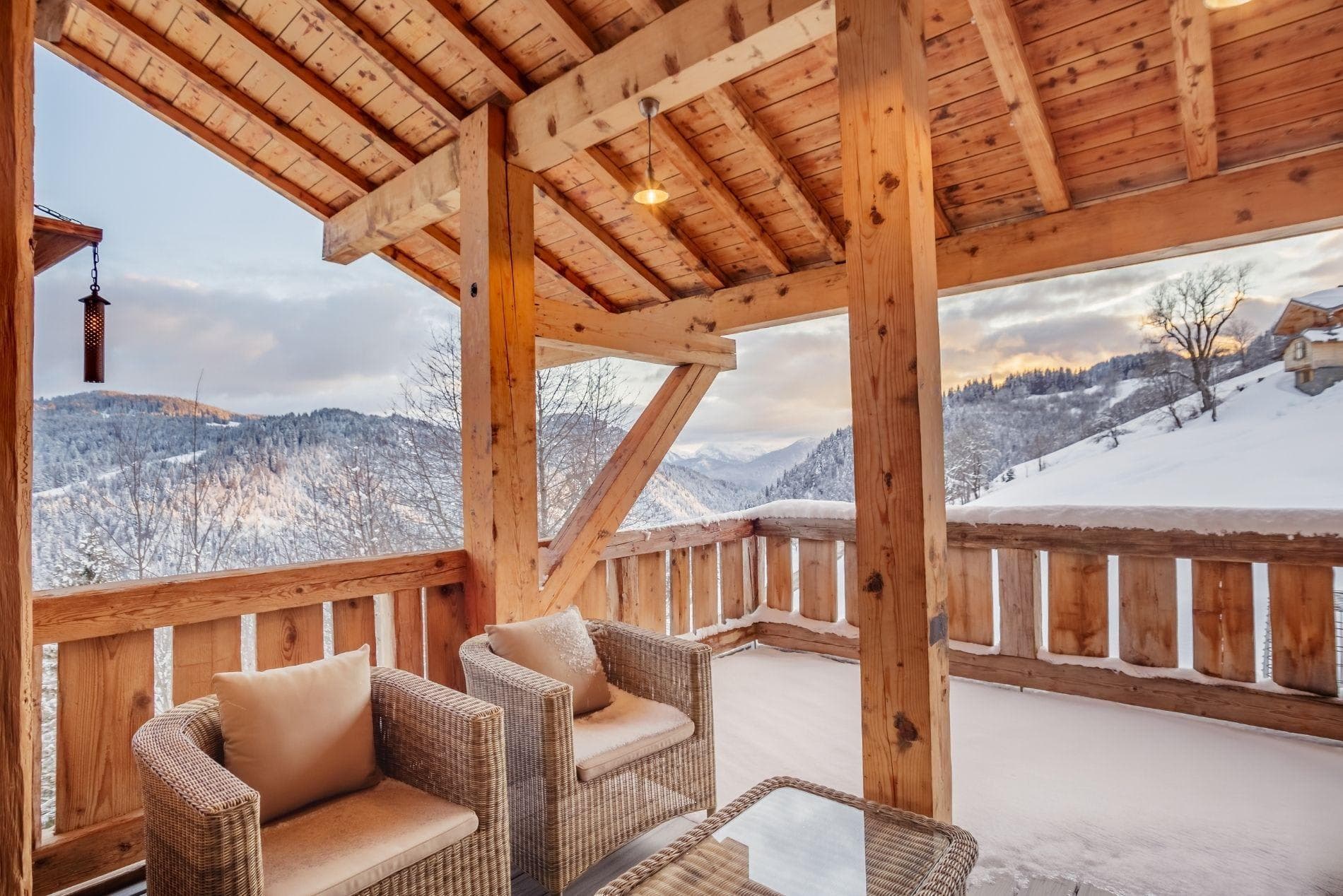 Covered timber balcony with wicker seating and mountain valley views