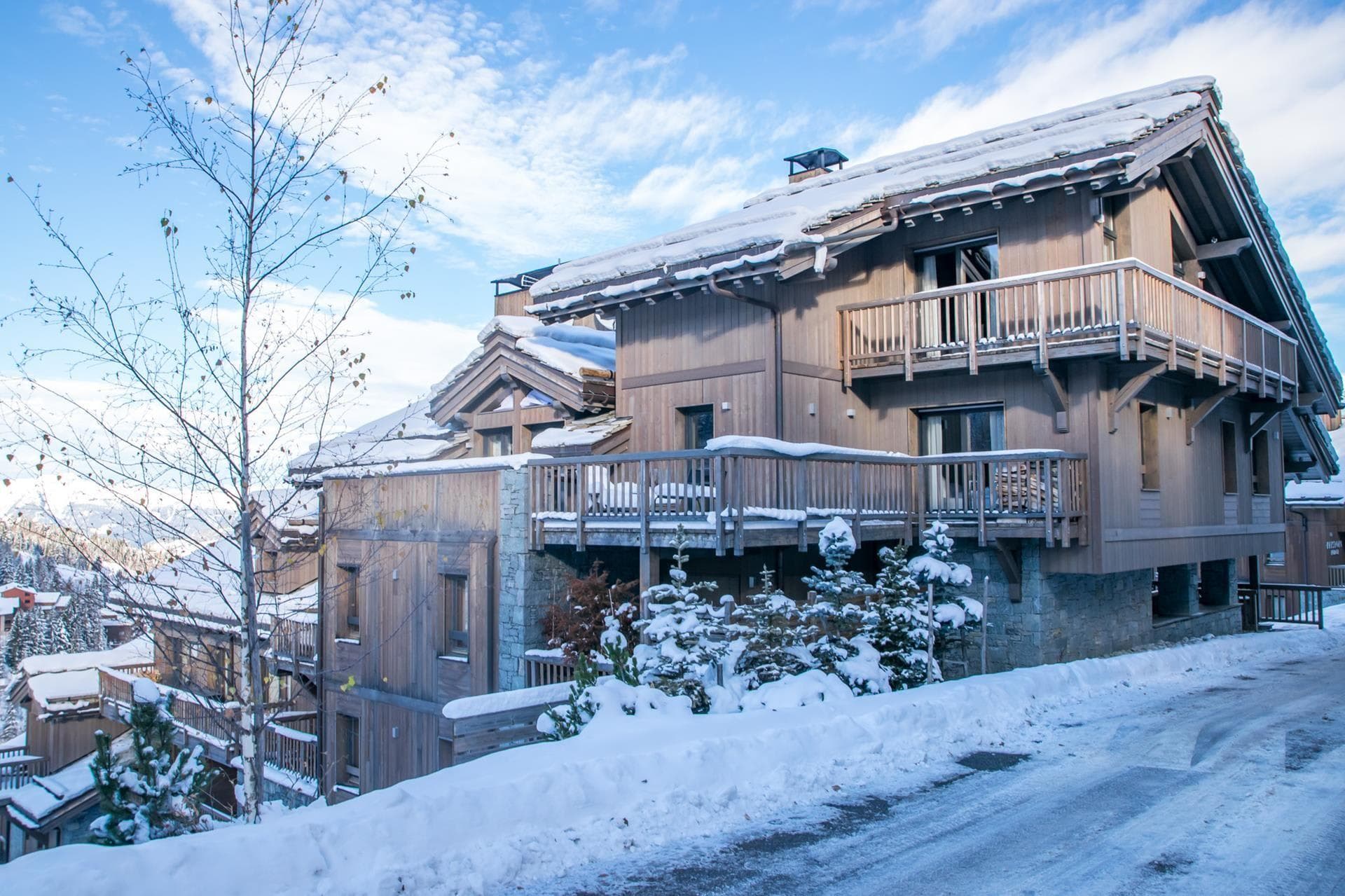 Ski-in chalet exterior featuring multiple private balconies and stone-clad foundation