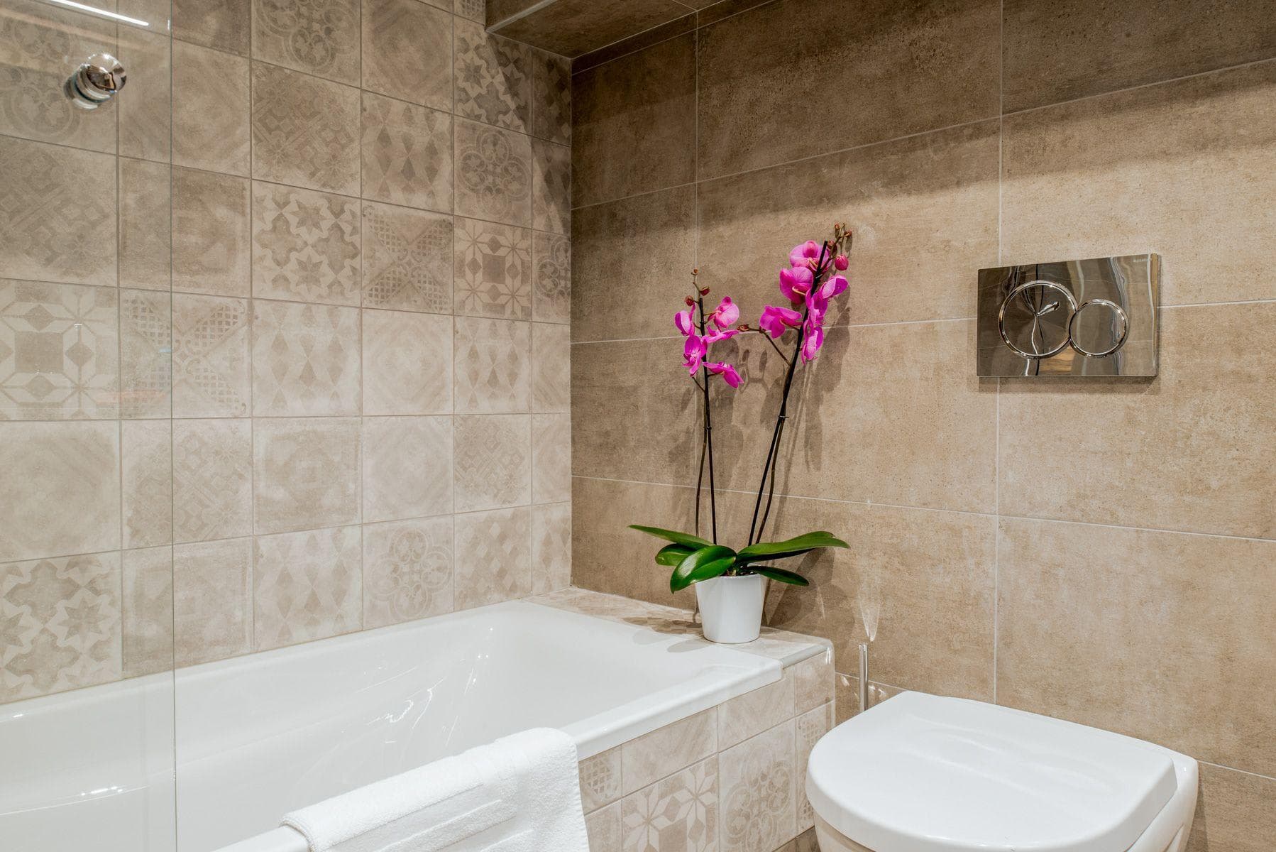 Bathroom with soaking tub, rainfall shower head, and patterned tile work