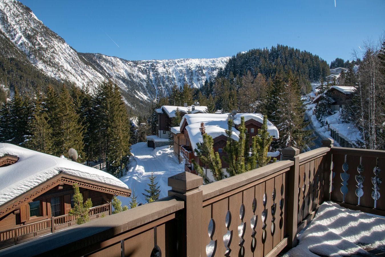 Deck with carved railings overlooking snow-covered valley and forested mountains