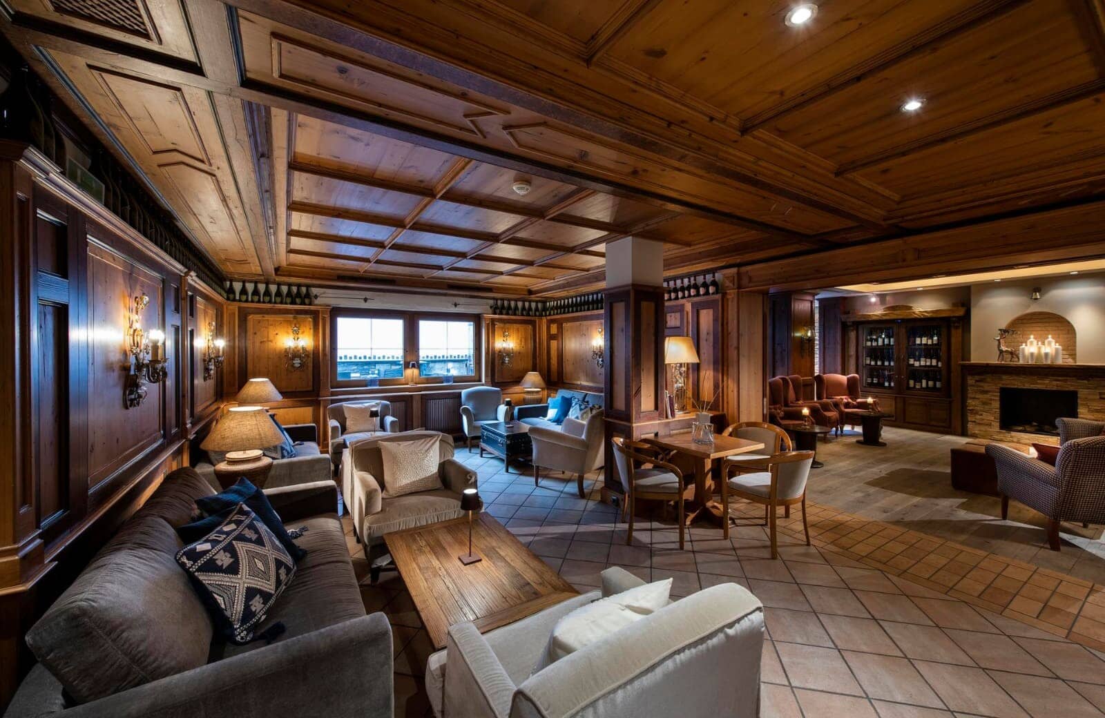 Wood-paneled lounge with coffered ceiling and fireplace seating