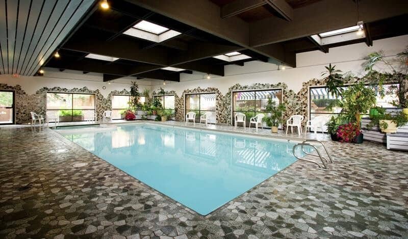 Indoor pool with stone masonry flooring and overhead skylights