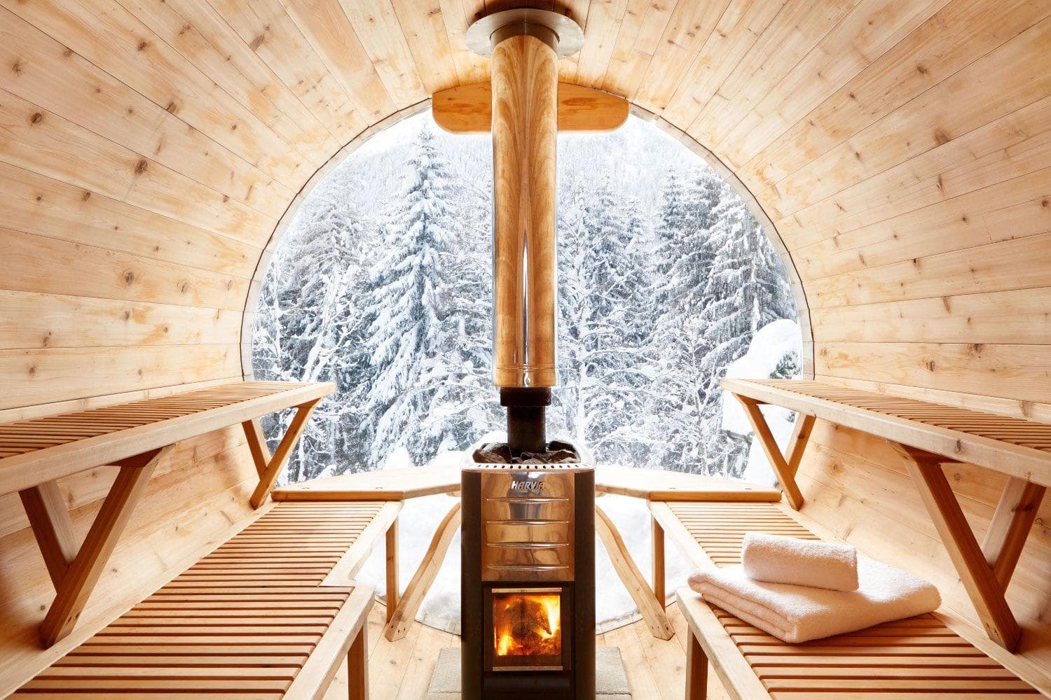 Wood-fired barrel sauna with Harvia heater and panoramic snow forest view