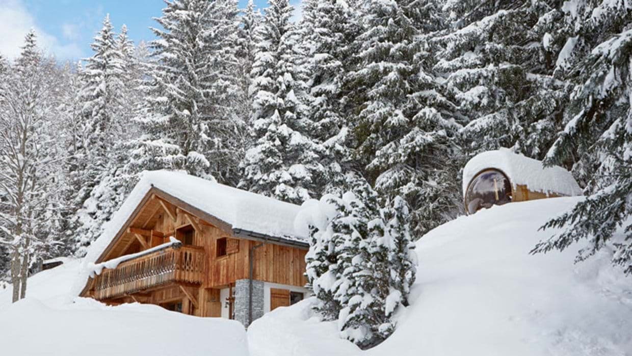 Timber chalet with outdoor barrel sauna featuring a panoramic window
