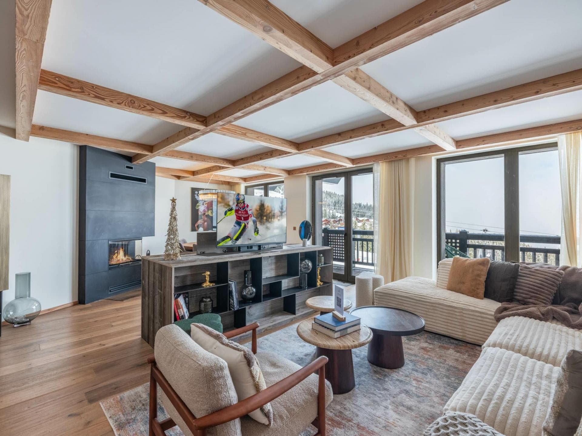 Living area with wood-beam ceiling, gas fireplace, and balcony access