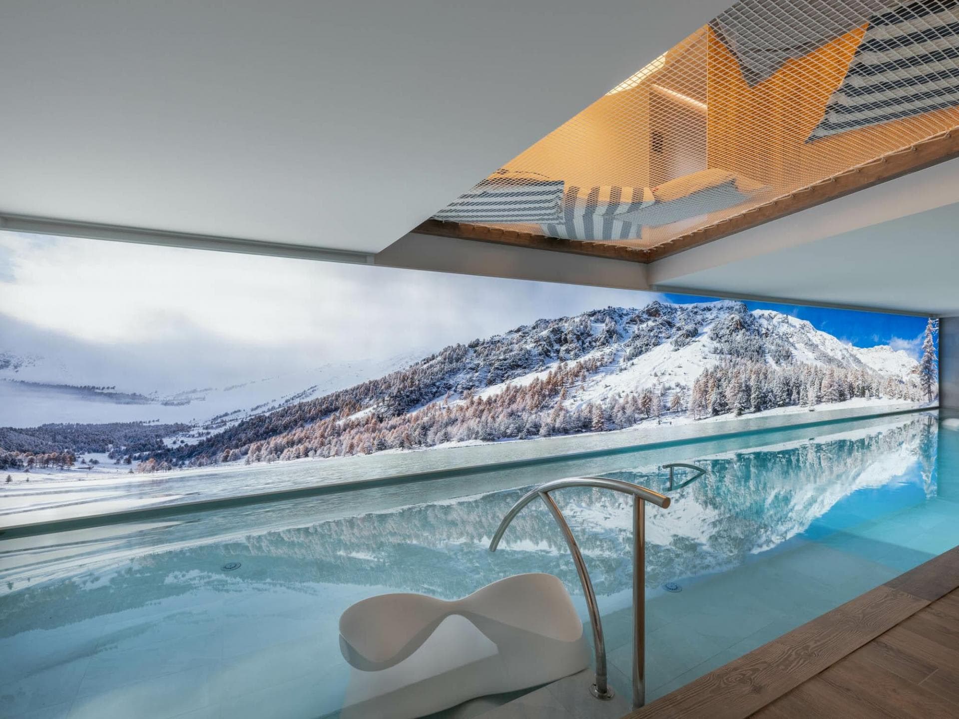 Indoor pool with panoramic mountain views and overhead hammock net