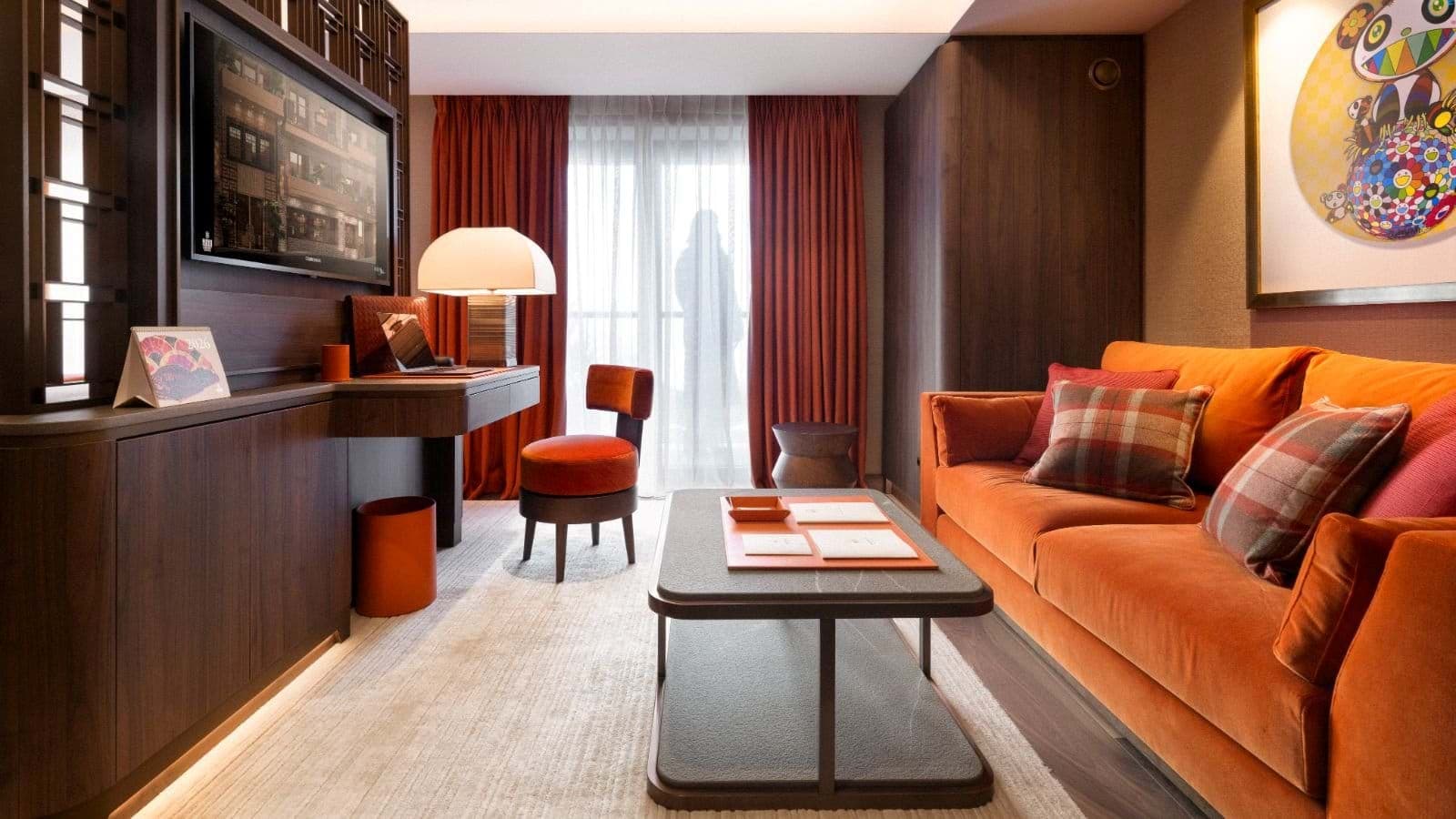 Living area with orange sofa, built-in desk, and balcony access